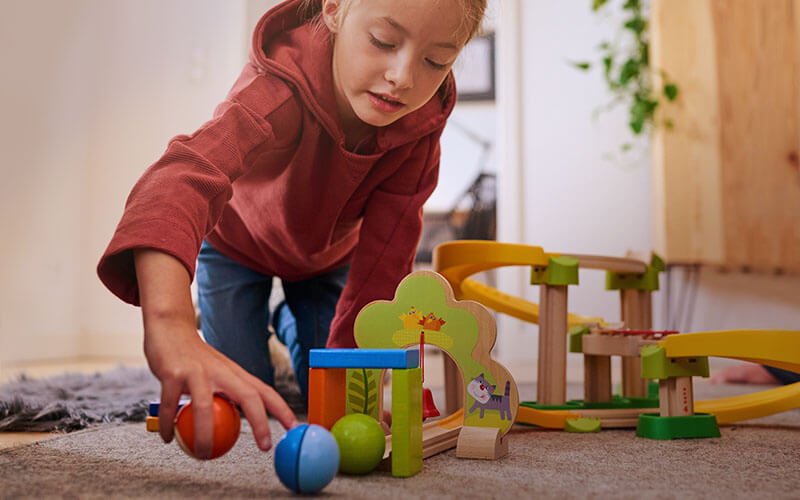 Girl on floor playing and collecting balls from the Kullerbu Sim-Sala-Kling Set 