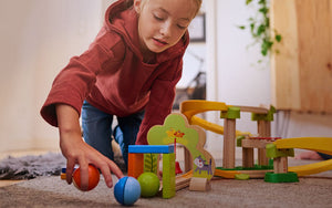 Girl on floor playing and collecting balls from the Kullerbu Sim-Sala-Kling Set 
